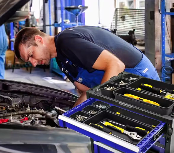 Mechanic working on a car with a toolbox open in a garage